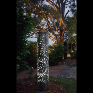 Round Steel Light Tower in Fanfare Pattern with Internal Lighting at Night